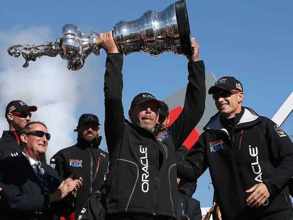Larry Ellison raising his team's yacht competition trophy. Ellison is fond of yachts.